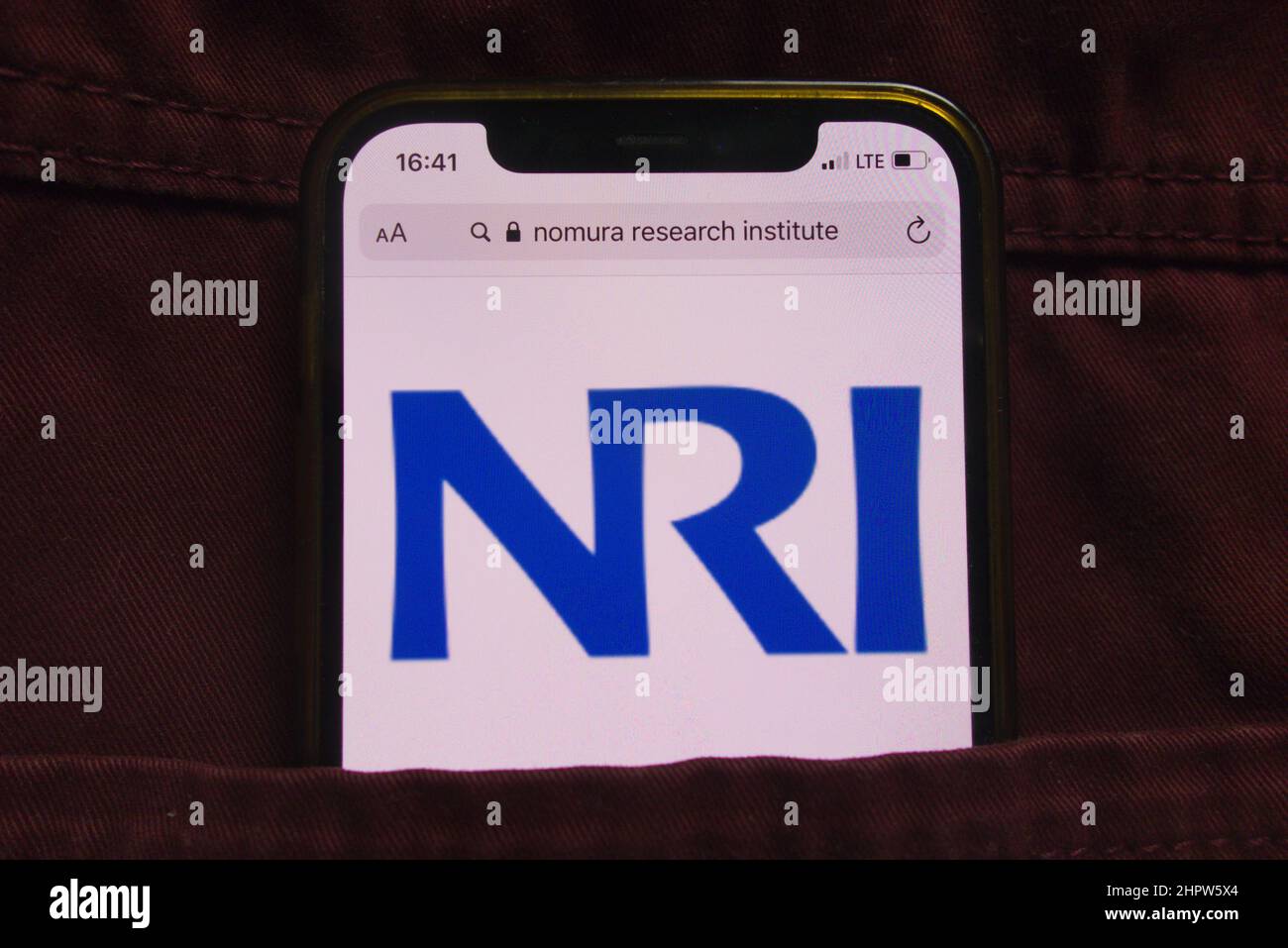 KONSKIE, POLEN - 22. Februar 2022: Das Logo von Nomura Research Institute Ltd wird auf dem Mobiltelefon in der Jeanstasche versteckt angezeigt Stockfoto