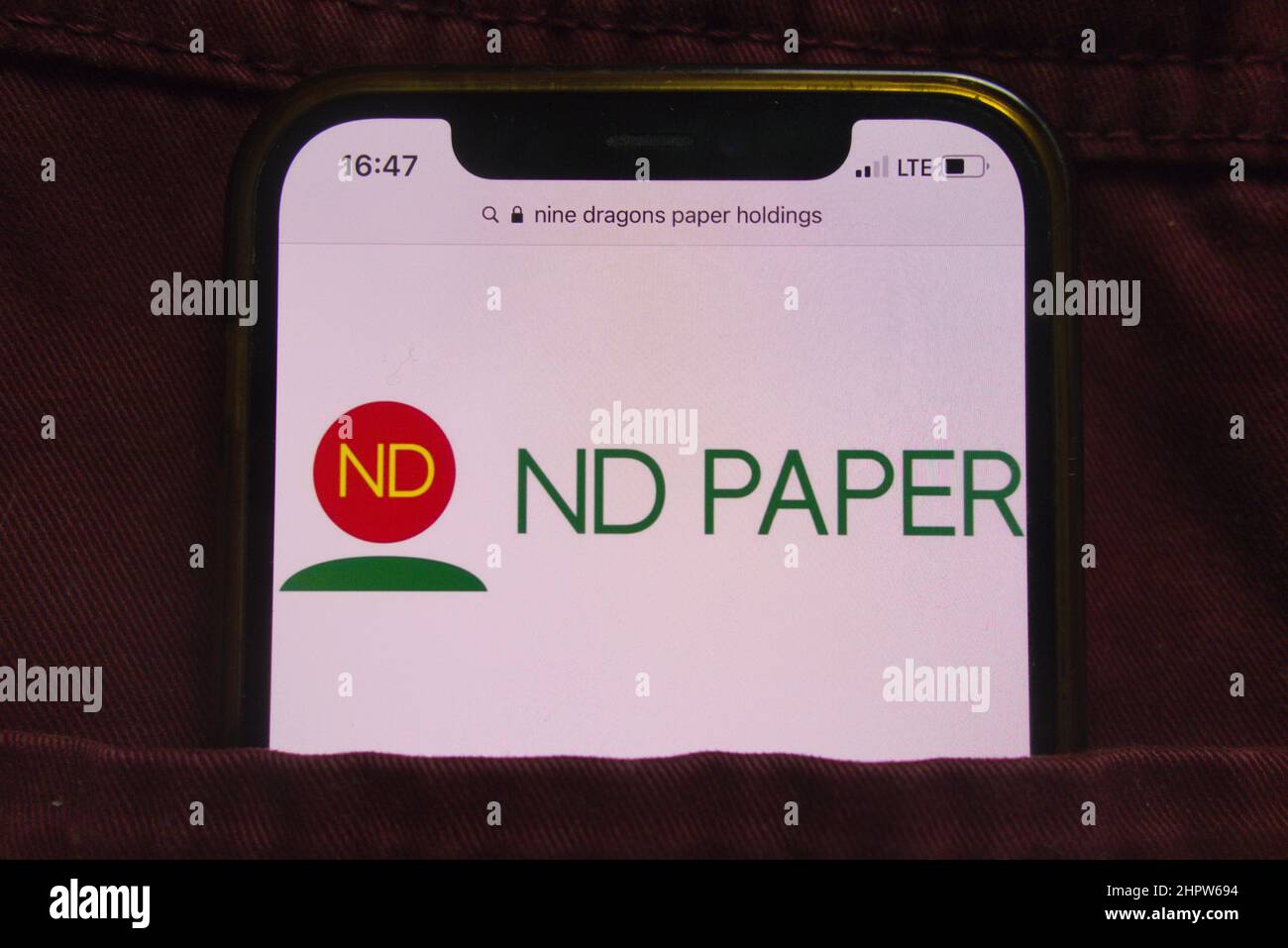 KONSKIE, POLEN - 22. Februar 2022: Das Logo von Nine Dragons Paper Holdings Limited wird auf dem Mobiltelefon in der Jeans-Tasche versteckt angezeigt Stockfoto