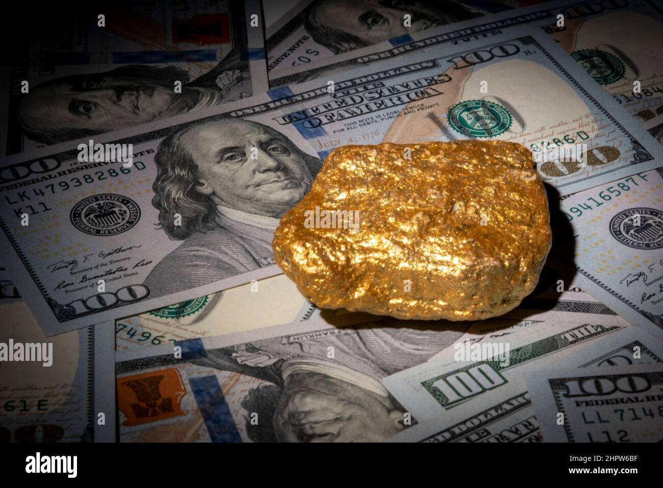Natürliche goldene Nuggets auf Hunderten US-Dollar-Scheinen. Investieren Sie in echtes Gold als Goldbarren. Nahaufnahme Gold finanzieren Vermögen oder Ersparnisse. Finanzkonzept Stockfoto
