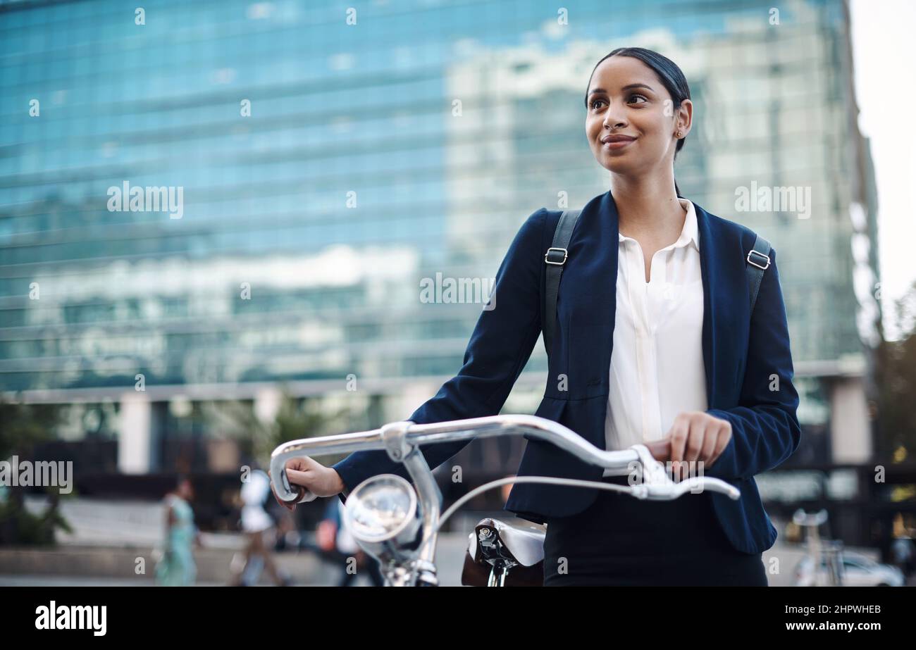 Willkommen in der Stadt, wo die Gelegenheit erwartet. Aufnahme einer jungen Geschäftsfrau, die mit dem Fahrrad durch die Stadt fährt. Stockfoto