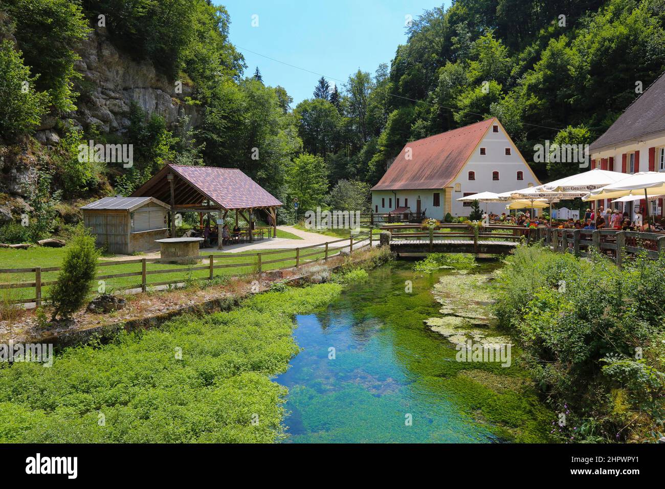 Wimsenmühle am Flusslauf der Ach, Bannmühle, rechts Gartenrestaurant mit Sonnenschirmen, Menschen, Hayingen-Wimsen Stockfoto