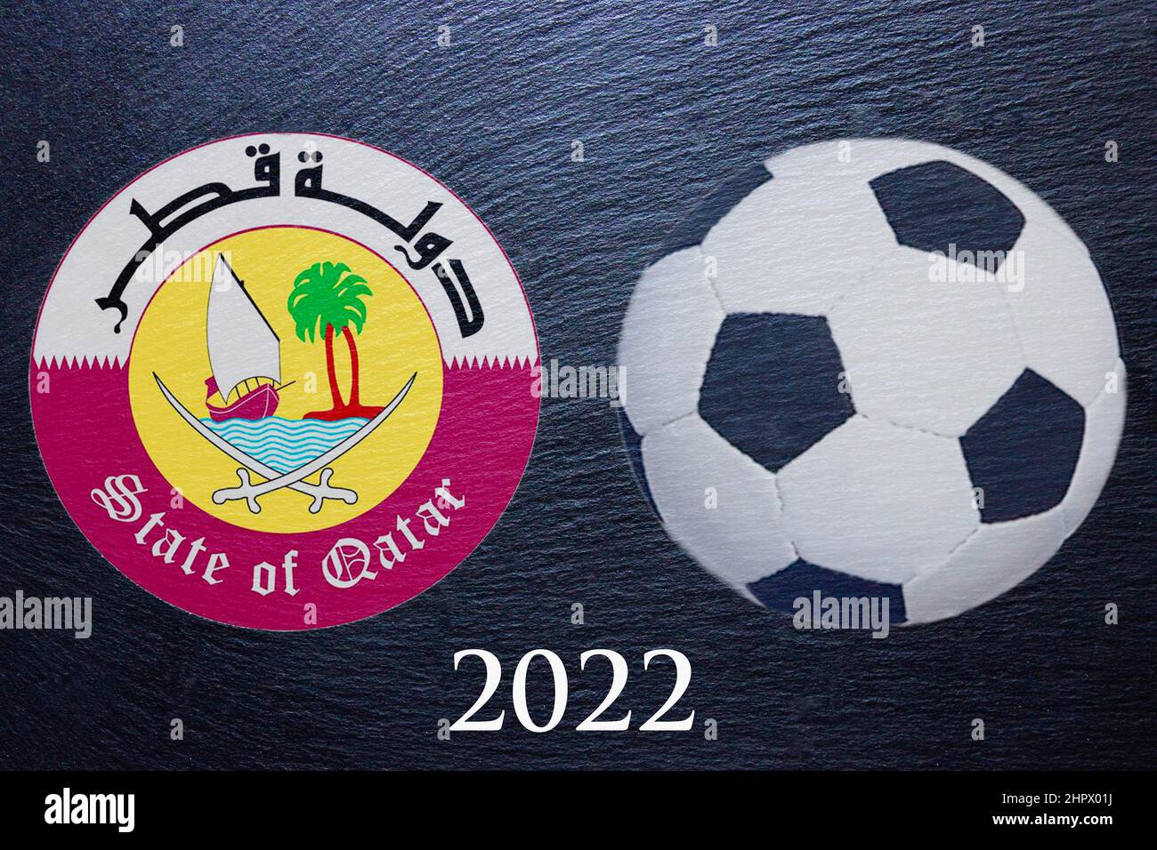 Ein Fußball, 2022 und das Wappen von Katar auf schwarzem Schiefer, Fotomontage Stockfoto