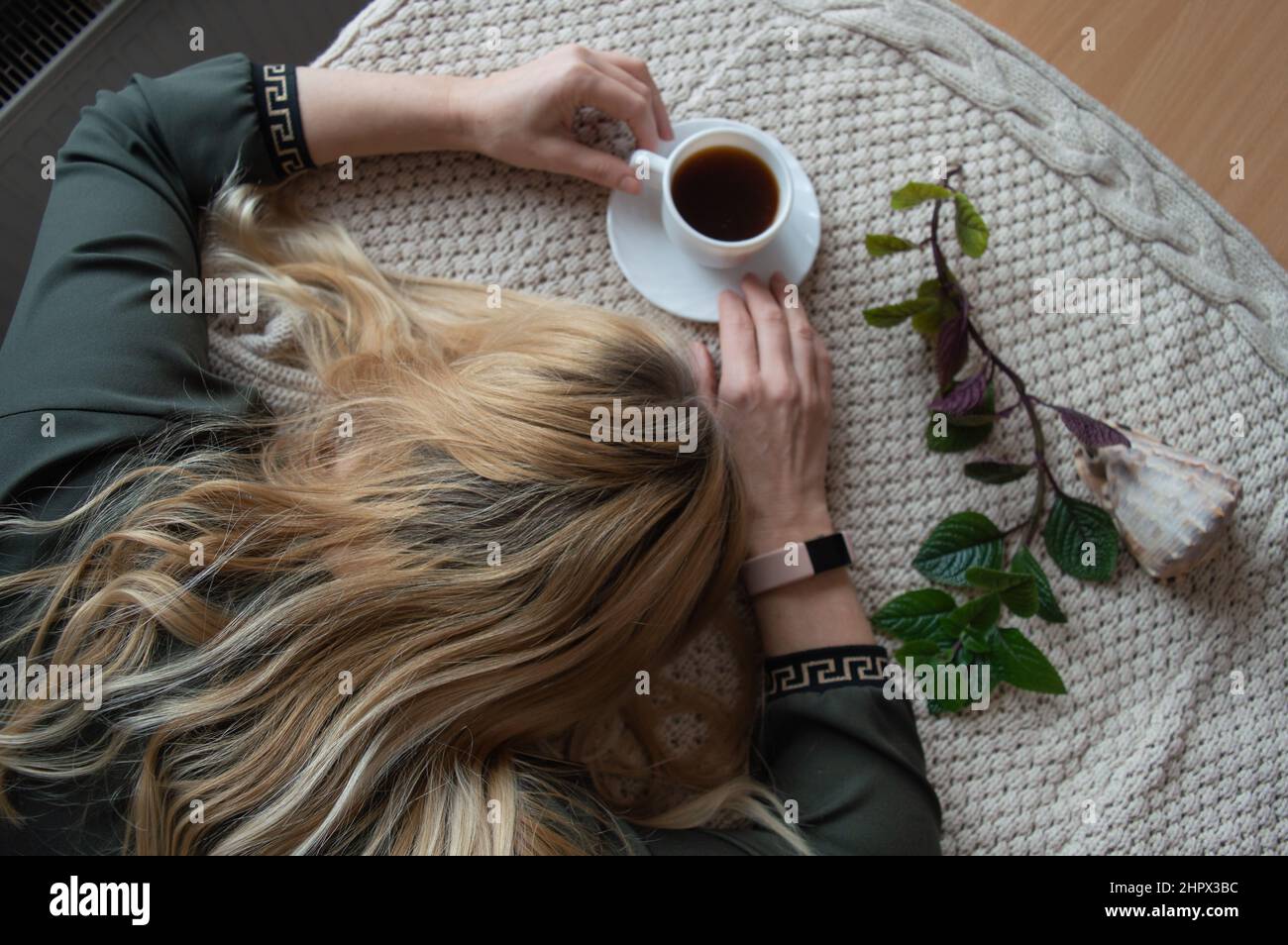 Frau müde eingeschlafen auf dem Tisch mit einer Tasse schwarzen Kaffee Stockfoto
