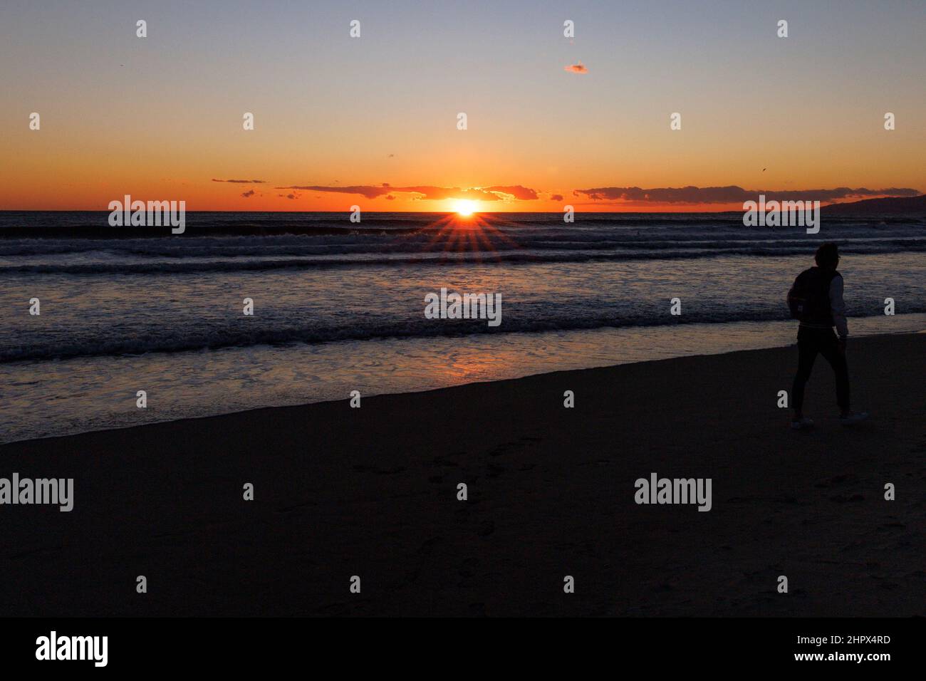 Venedig, Kalifornien, USA. 23rd. Februar 2022. Ein Mann geht bei Sonnenuntergang am Strand, als ein vorübergehender Sturm kalte Temperaturen und klaren Himmel brachte, aber kein Regen, da die Dürre in Kalifornien weiter geht (Foto: © Jonathan Alcorn/ZUMA Press Wire) Stockfoto