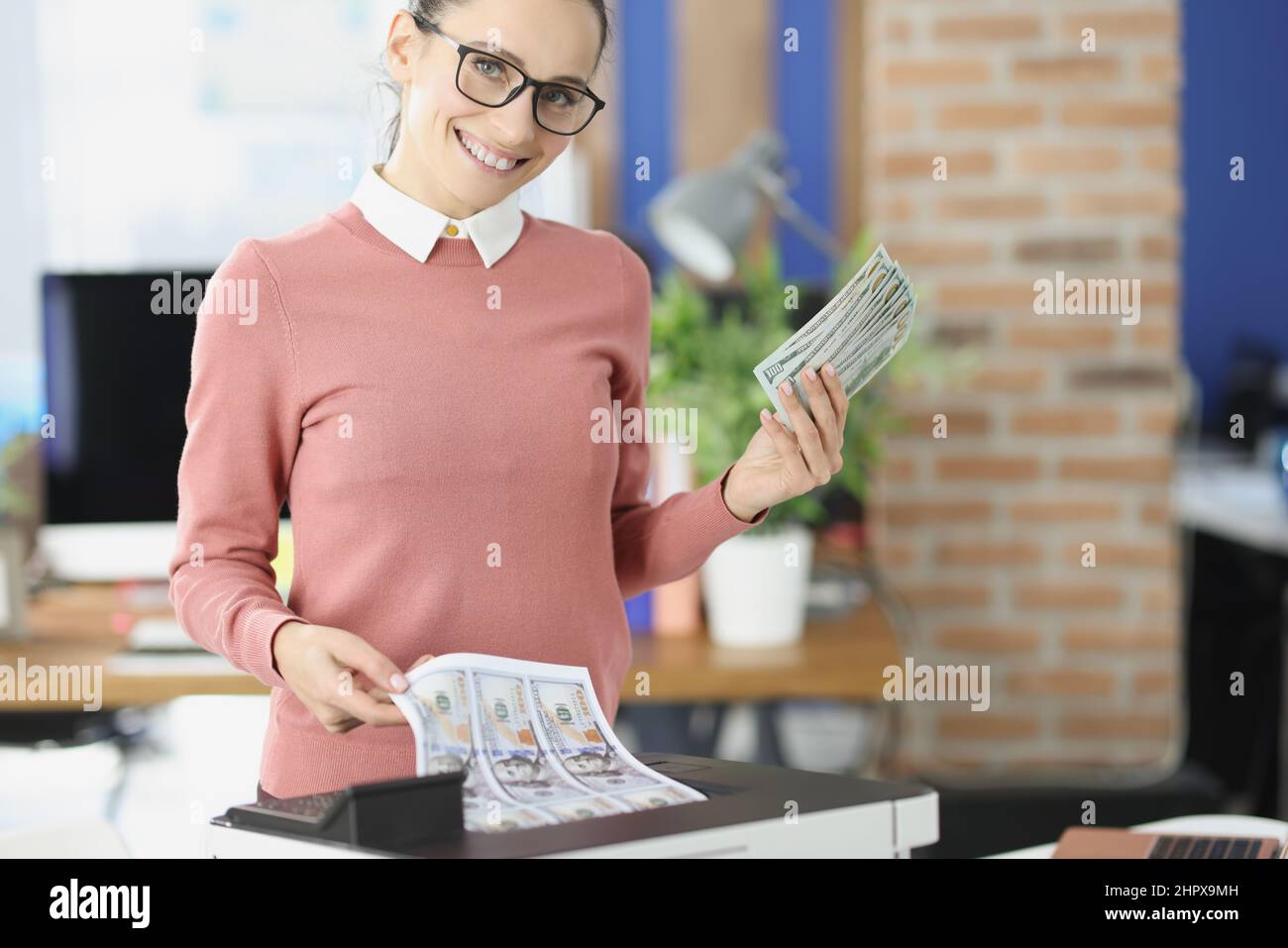 Im Büro druckt eine glückliche Frau Dollar auf einen Drucker Stockfoto