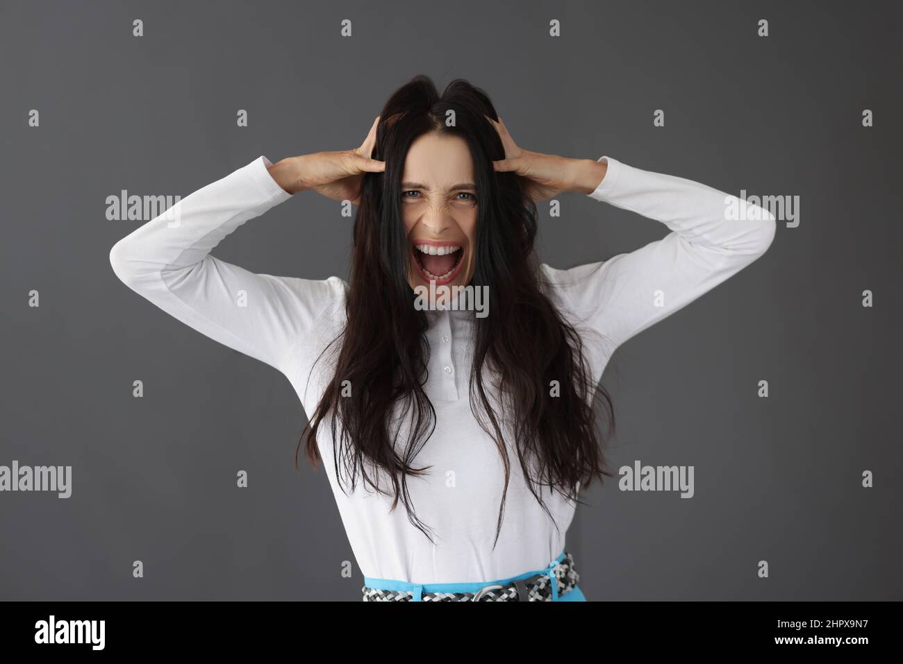 Schöne Brünette Frau schreit hält ihren Kopf Stockfoto