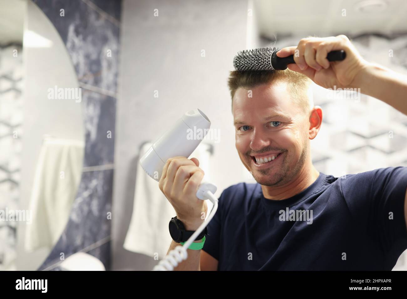 Glücklicher Mann, der zu Hause sein eigenes Föhnen macht Stockfoto
