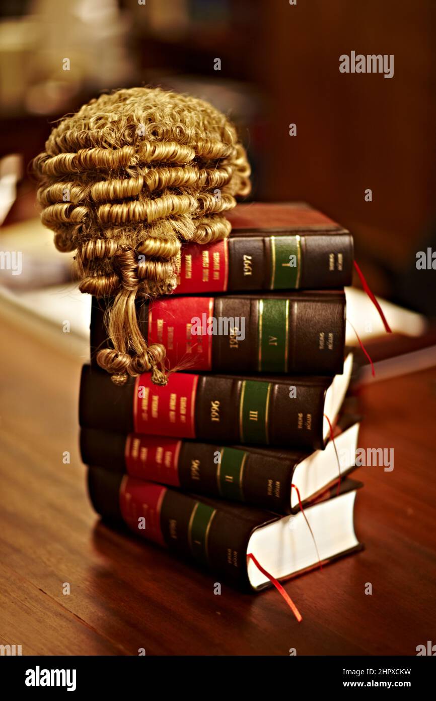 Die Kenntnis des Gesetzes ist für ein faires Verfahren von entscheidender Bedeutung. Aufnahme von juristischen Büchern und einer Perücke auf einem Tisch. Stockfoto