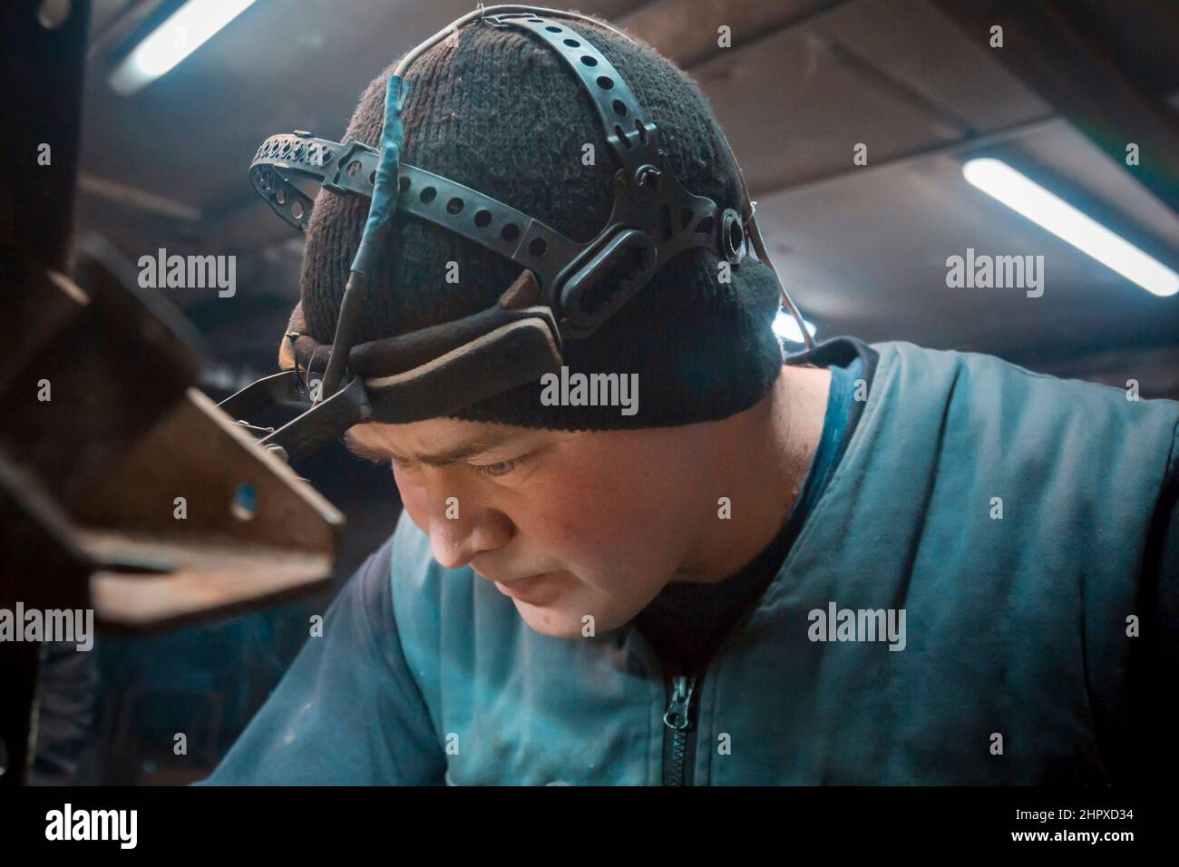 Porträt eines Argon-Schweißers mit einer Stirnlampe auf dem Kopf am Arbeitsplatz Stockfoto