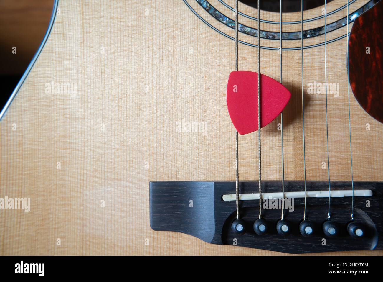 Red Triangle Gitarre Pick auf einer akustischen Gitarre Stockfoto