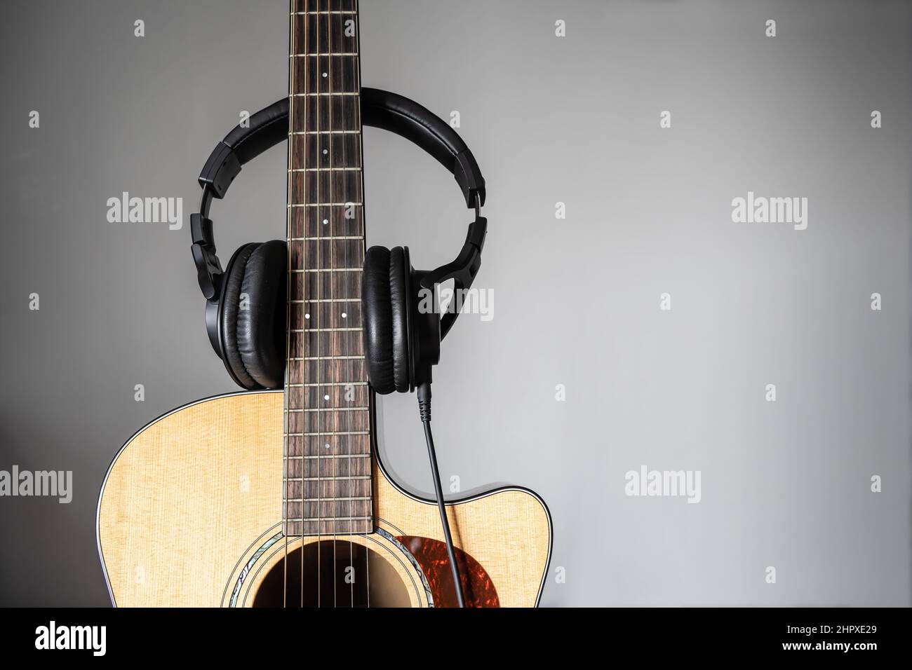 Akustische Gitarre und Ohrhörer mit grauem Hintergrund Stockfoto