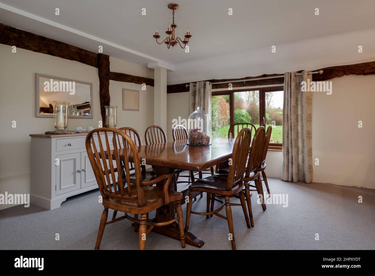 Esszimmer im renovierten alten Haus mit freiliegenden Holzbalken, Esstisch und Stühlen aus Holz und hell in Weißtönen eingerichtet Stockfoto