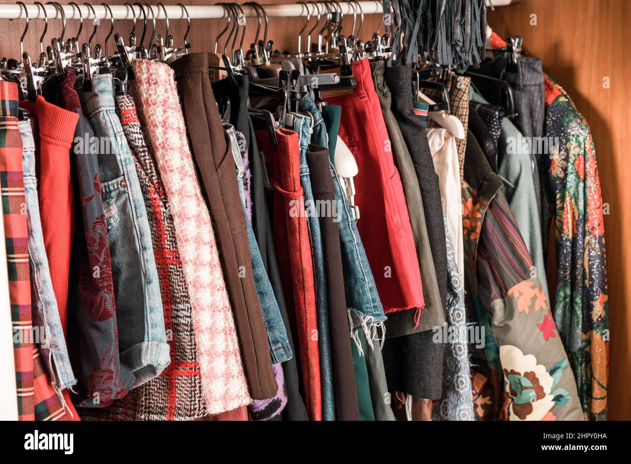Verschiedene bunte weibliche Kleidung hängen in einem Schrank oder begehbaren Kleiderschrank innen auf einer Schiene in der Nähe Stockfoto