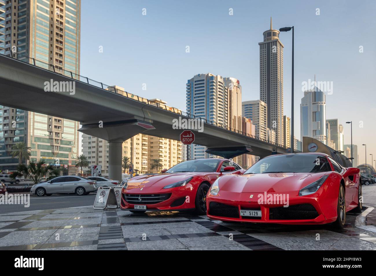 2 rote Ferrari's in der Nähe der Sheikh Zayed Road, mit der U-Bahn-Linie in der Nähe von Dubai, Vereinigte Arabische Emirate (VAE) geparkt. Stockfoto