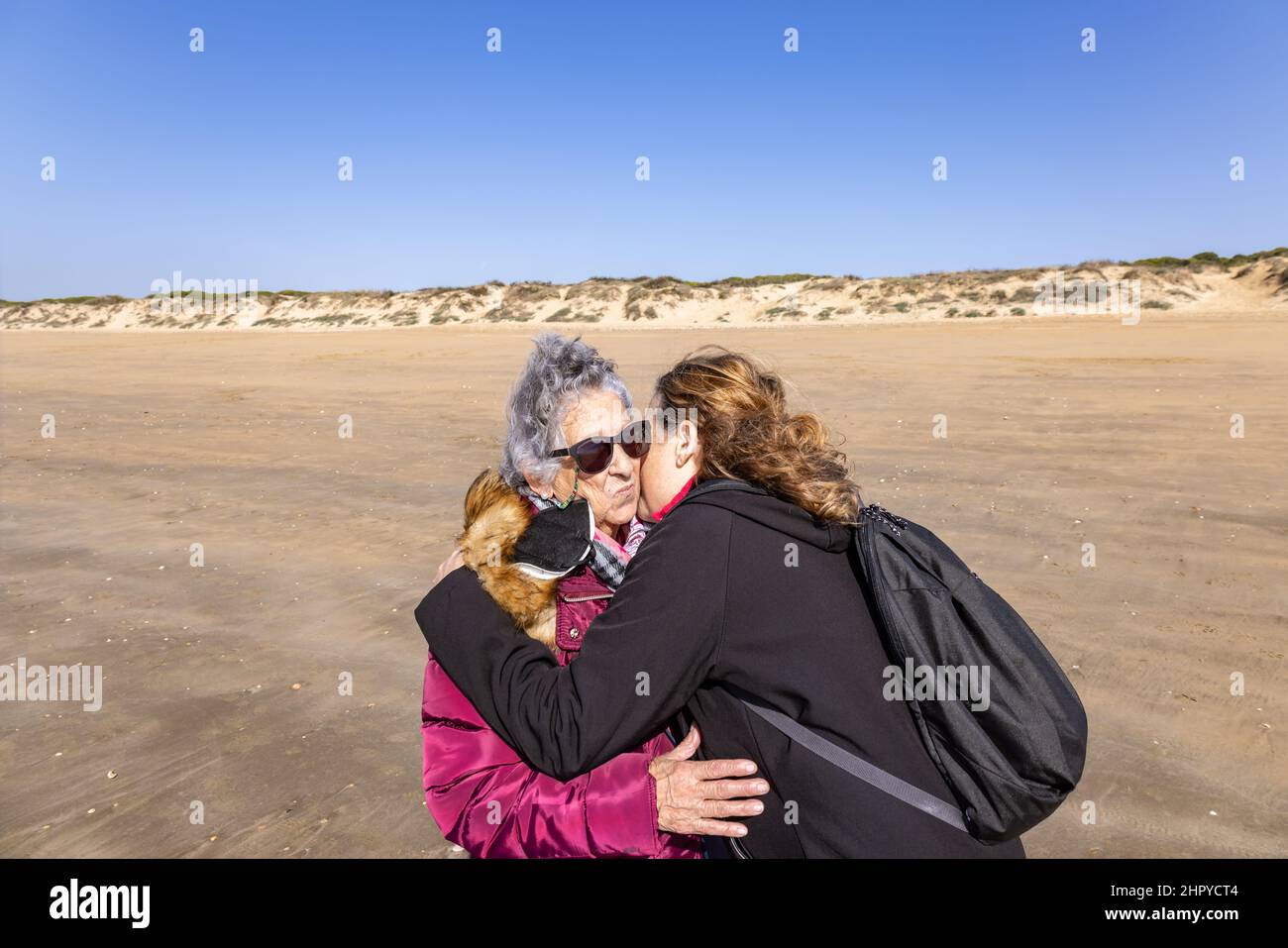 Eine reife Frau küsst und umarmt ihre ältere Mutter am Strand Stockfoto