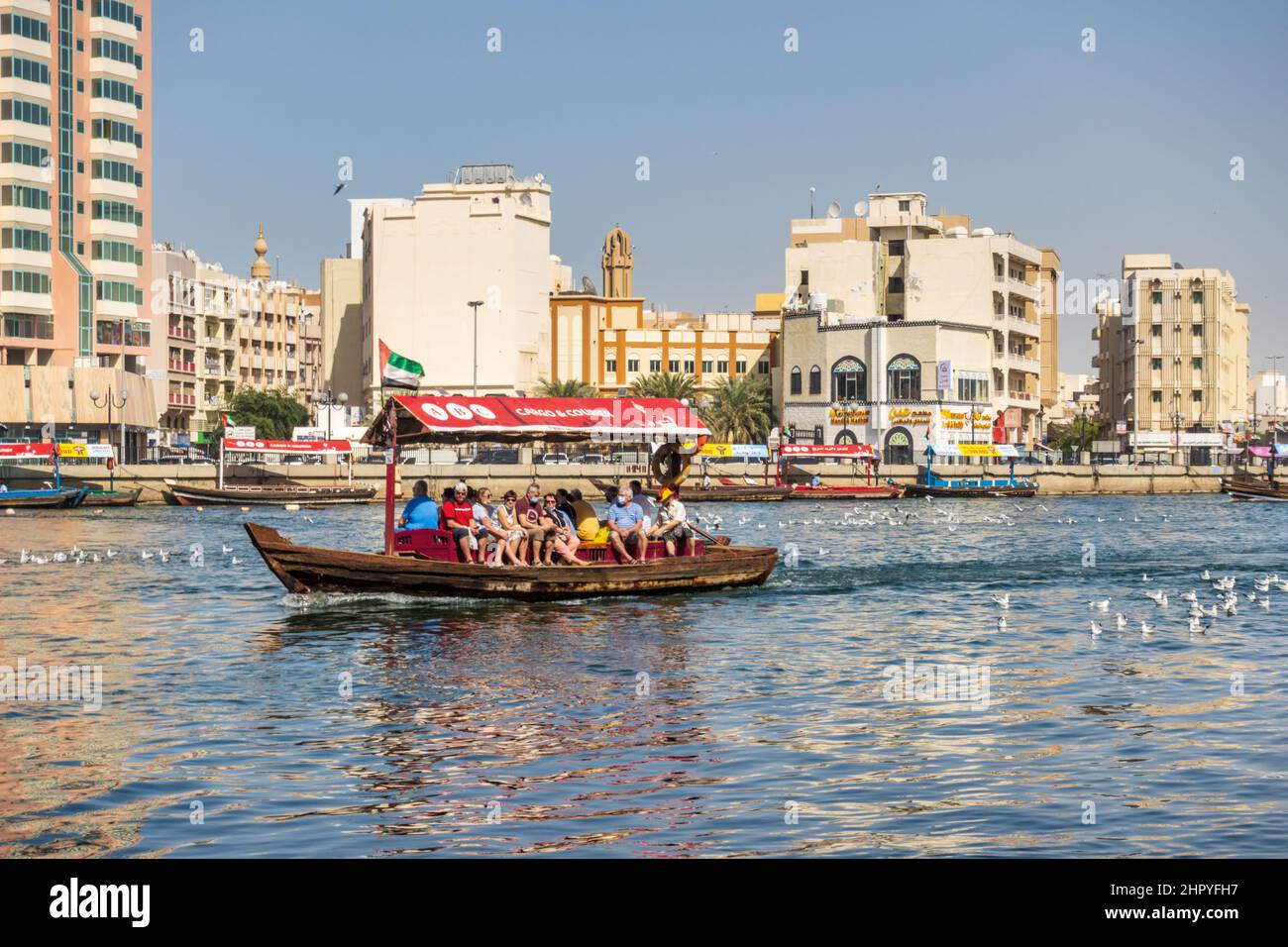 Touristen, die den Dubai Creek in einem traditionellen Abra-Boot in der Stadt Dubai, Vereinigte Arabische Emirate überqueren. Stockfoto
