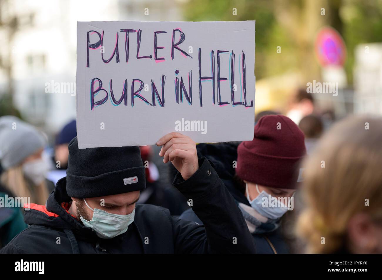Hamburg, Deutschland. 24th. Februar 2022. Die Teilnehmer eines Protestes gegen die russische Invasion in der Ukraine stehen vor dem russischen Generalkonsulat. Ein Demonstrator hält ein Schild mit der Aufschrift „Putler burn in hell“. Putler ist ein Neologismus, der sich aus den Namen „Putin“ und „Hitler“ setzt. Quelle: Jonas Walzberg/dpa/Alamy Live News Stockfoto