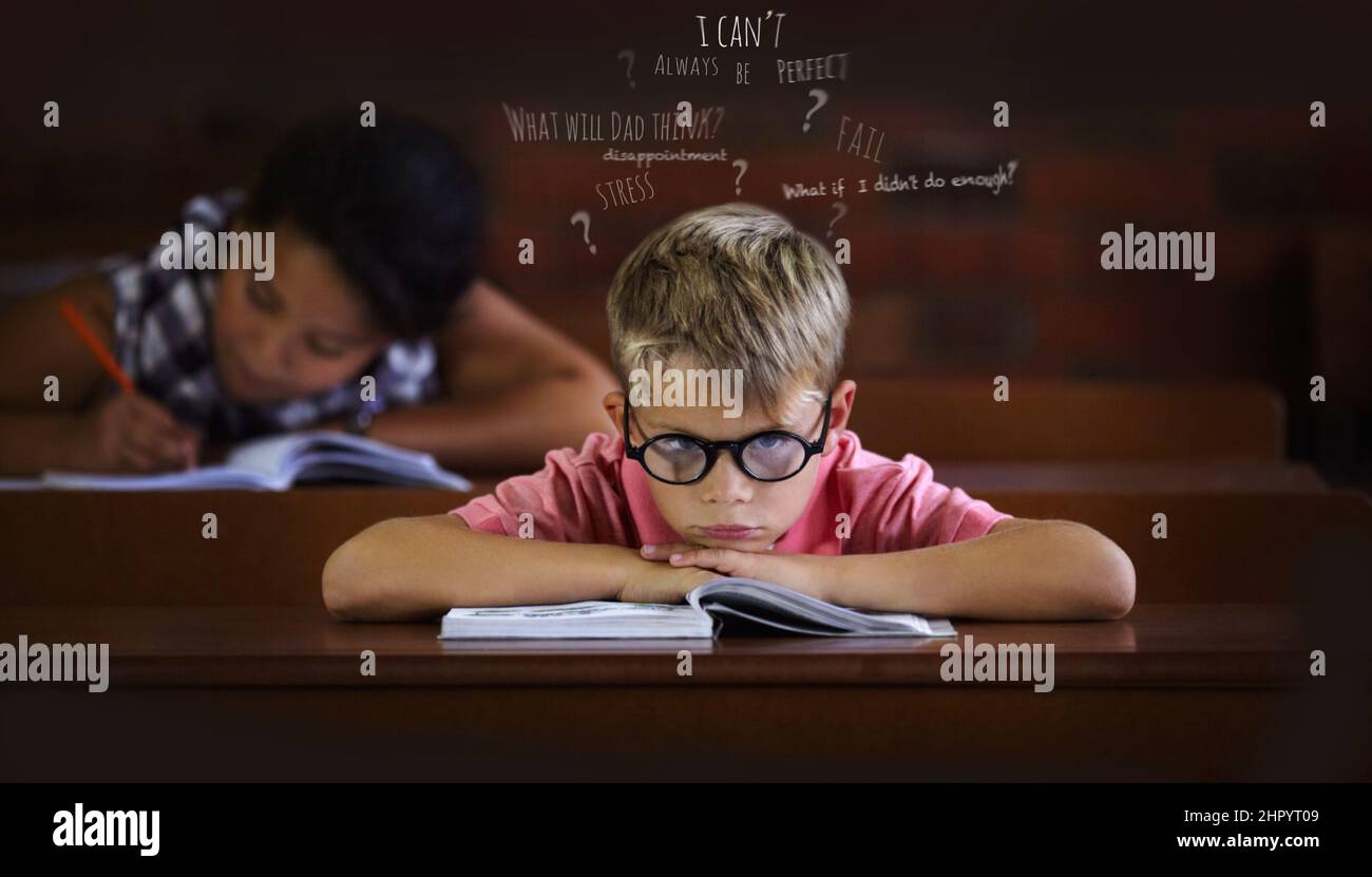 Verwirrt und zu kämpfen, um zu lernen - Lernbehinderungen. Kleiner Junge, der sich im Klassenzimmer von Langeweile überwältigt fühlt. Stockfoto