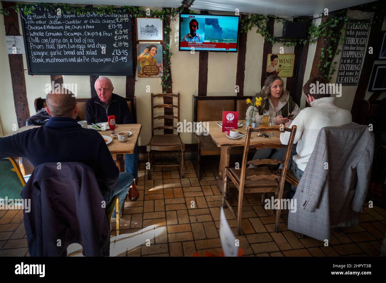 Russland erobert die Ukraine, im Fernsehen in der Weinbar Thaxted Essex, Großbritannien. 24th. Februar 2022. Während Kunden der Parrishes Wine Bar in Thaxted Essex UK ihr Mittagessen einnehmen, zeigt das Fernsehgerät Berichte auf der BBC, die die Invasion der Ukraine durch Russland heute zeigen. Kredit: BRIAN HARRIS/Alamy Live Nachrichten Stockfoto