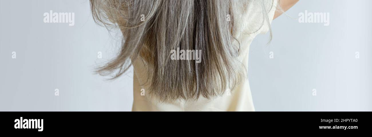 Frau mittleren Alters zeigt lange lose graue Haare stehen auf hellem Hintergrund Stockfoto