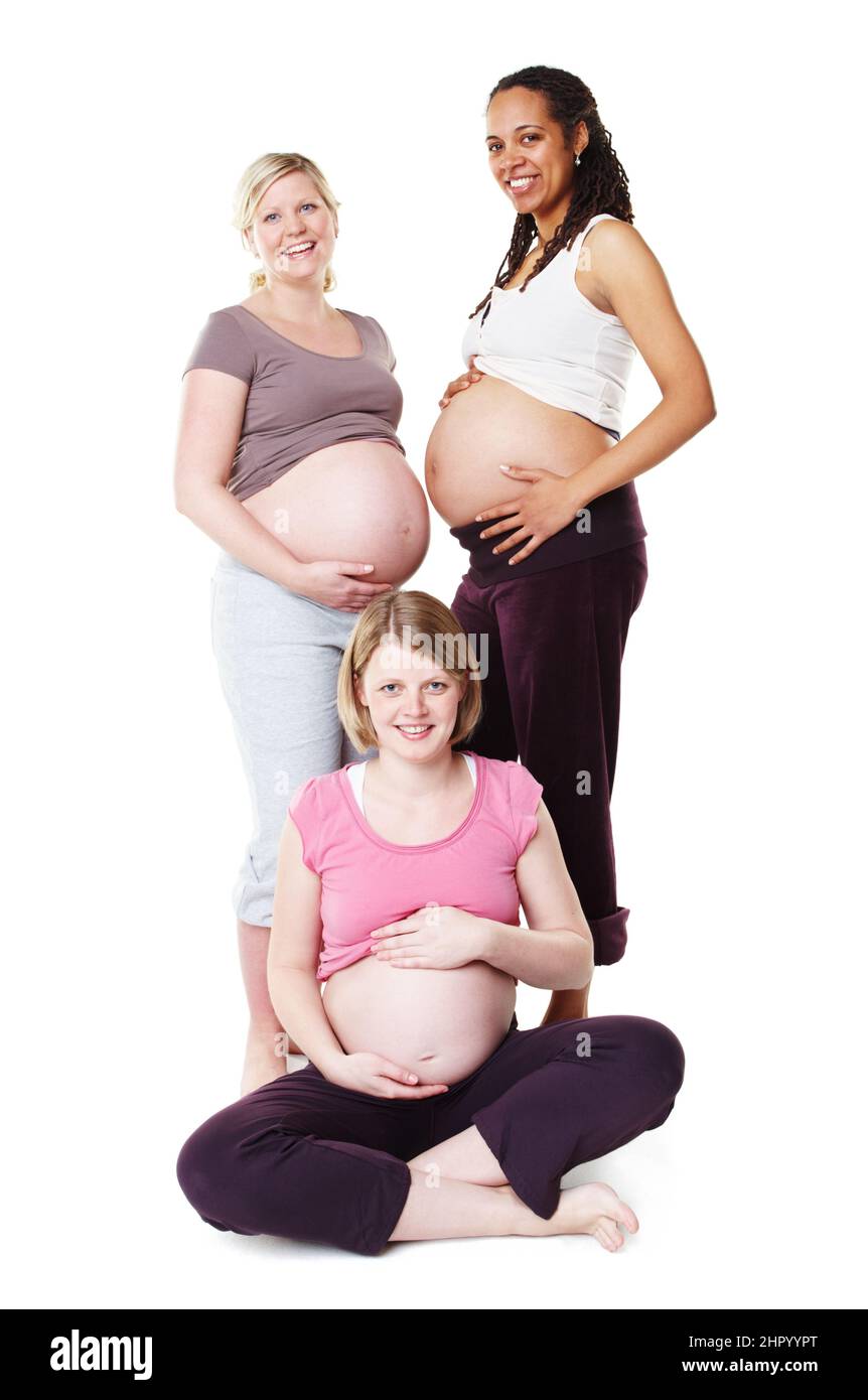Sieht wunderschön schwanger aus. Schwangere zeigen ihre Bäuche zusammen, während sie isoliert auf Weiß stehen. Stockfoto
