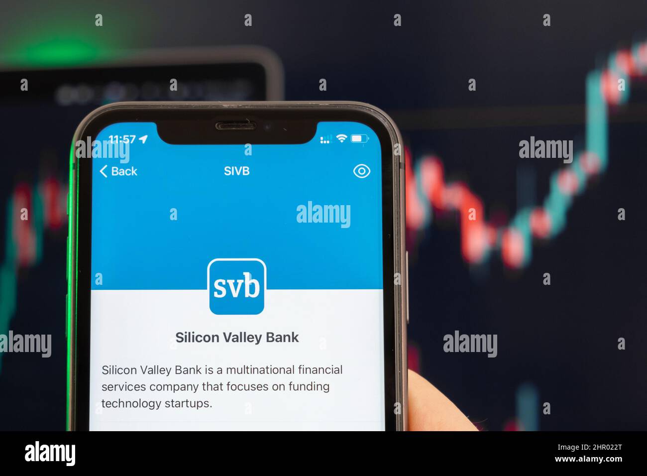 Der Aktienkurs der SVB der Silicon Valley Bank steigt am Handelsmarkt mit einem Balkendiagramm im Trenddiagramm im Hintergrund. Mann mit Mobiltelefon und Firmenlogo, Februar 2022, San Francisco, USA Stockfoto