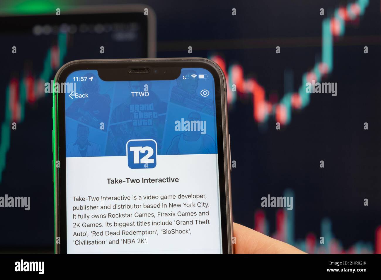 Nehmen wir zwei interaktive T2-Aktienkursen, die am Trading-Markt steigen, mit einem Balkendiagramm mit Aufwärtstrend-Linien im Hintergrund. Mann mit Mobiltelefon und Firmenlogo, Februar 2022, San Francisco, USA Stockfoto