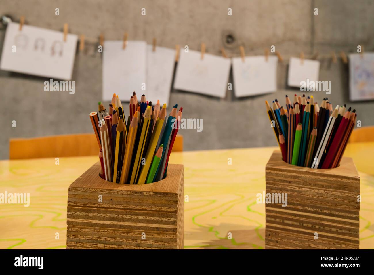 Bleistifte zum Färben in einem Holzkrug mit Kunstwerken im Hintergrund Stockfoto