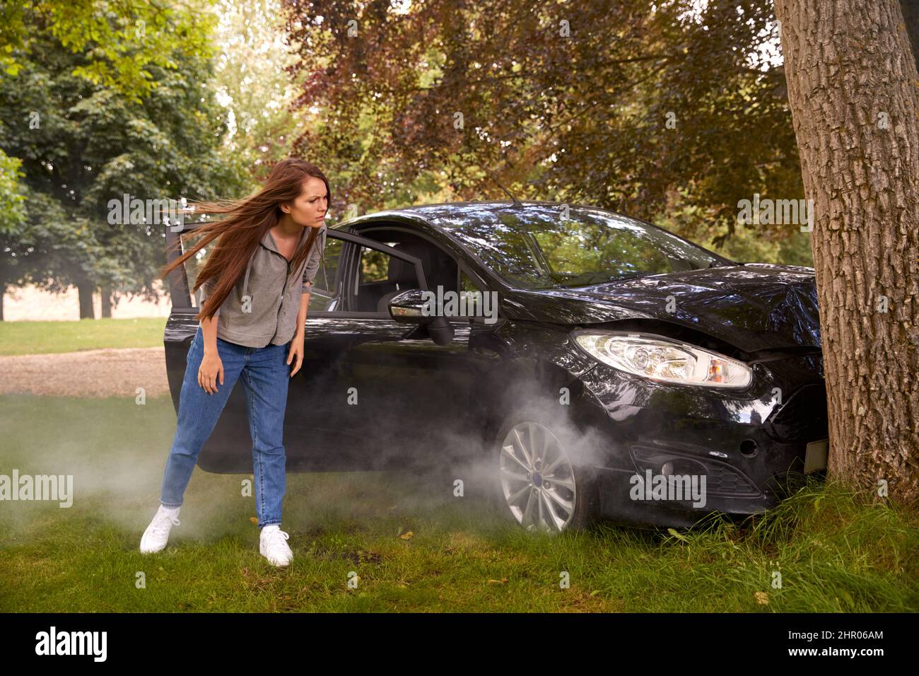 Die Frau Neben Dem Auto Stürzte In Den Baum Und Inspiziert Unfallschäden Stockfoto