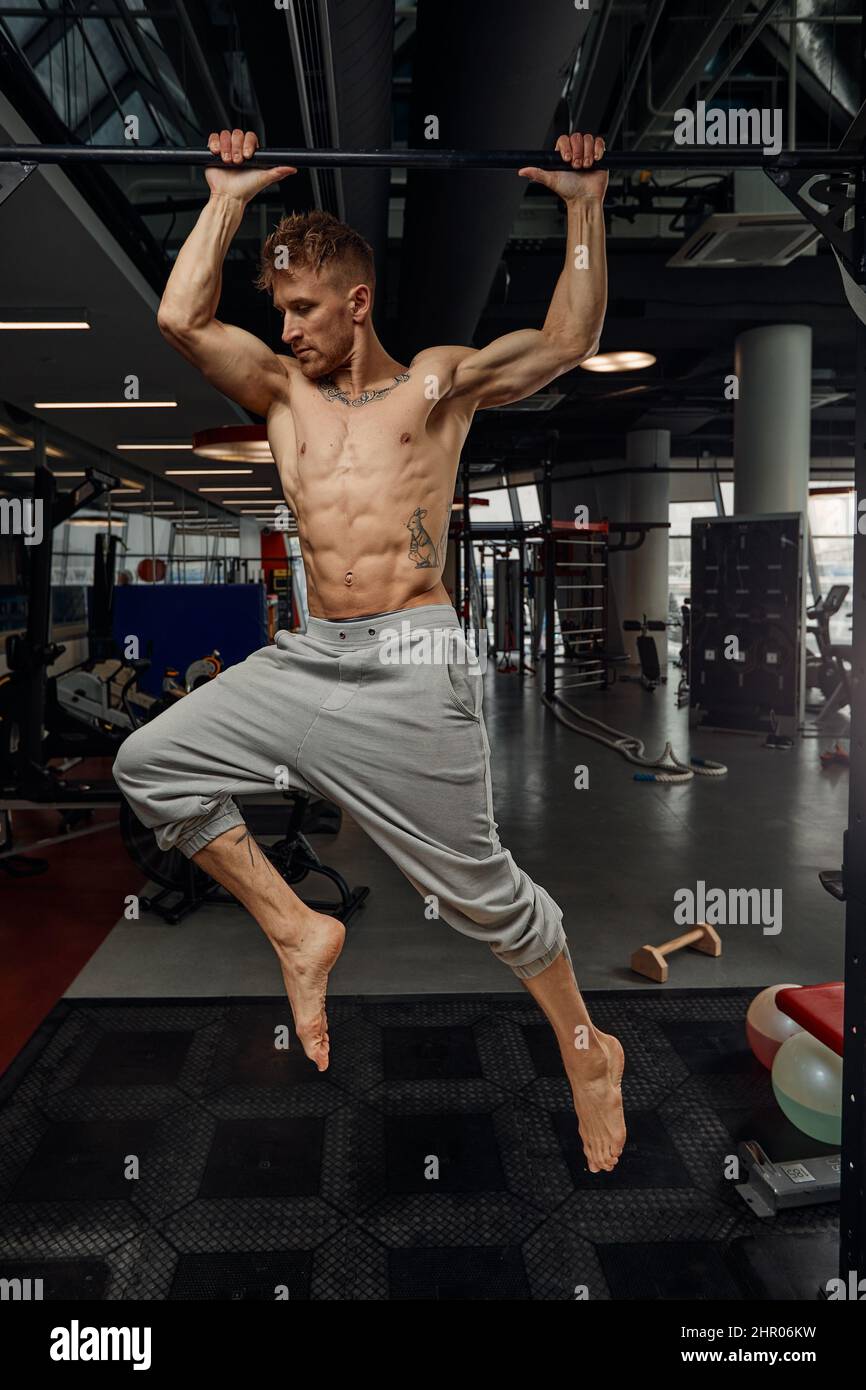 Muskulöser starker Mann trainiert in der Sporthalle, Mann macht horizontale Liegestütze mit Gittern im Fitnessstudio. Im Hintergrund Fitnessstudio mit Platz zum Kopieren Stockfoto