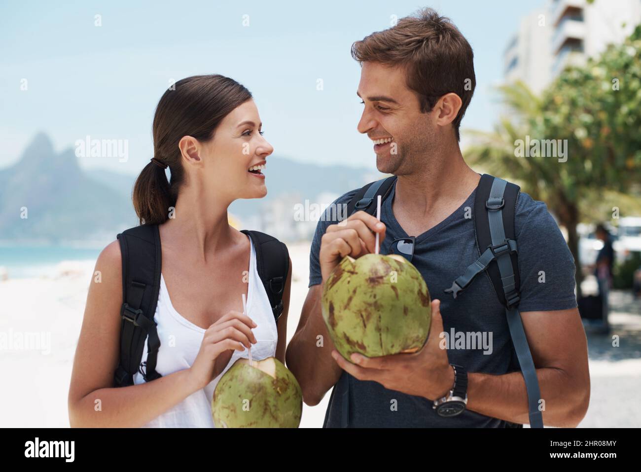 Wir hatten eine tolle Zeit im Paradies. Das junge Paar genießt einen Drink von einer Kokosnuss, während es einen Tag am Strand genießt. Stockfoto