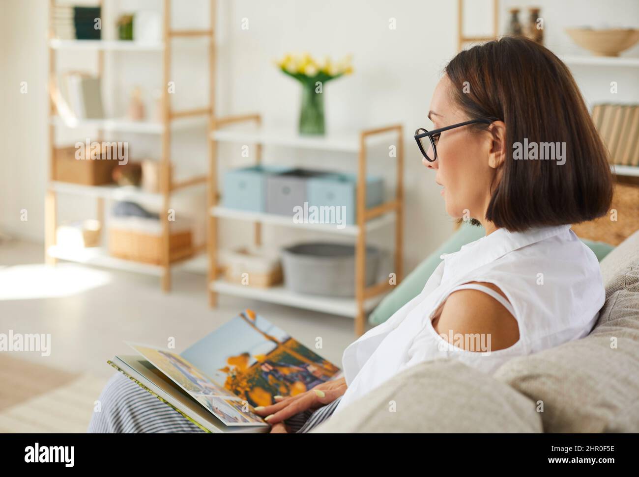 Frau schaut sich ihr Familienfotoalbum an und erinnert sich an wunderbare Momente in ihrem Leben. Stockfoto