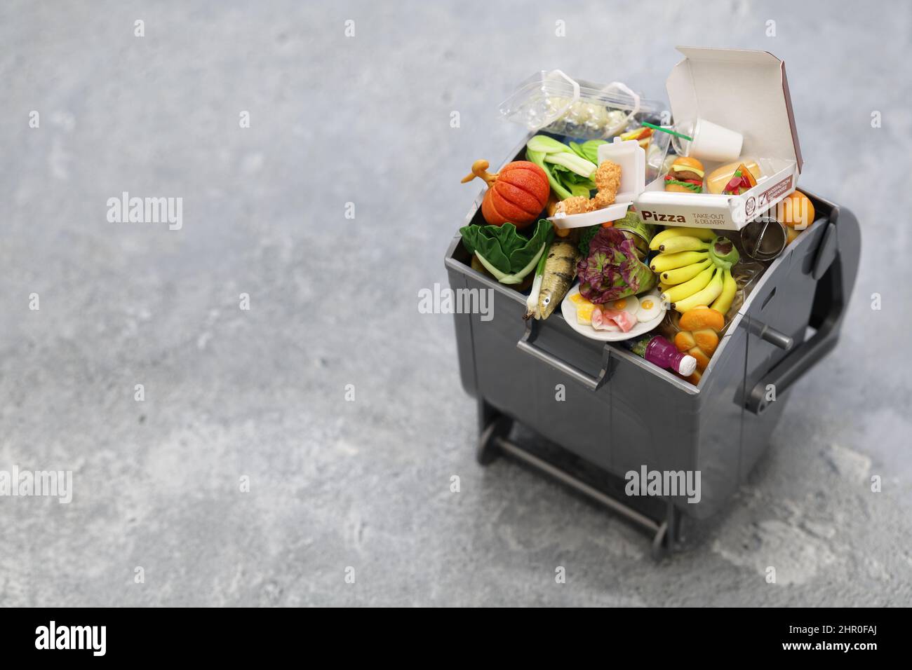 Mülltonne, Bild von Lebensmittelabfällen in Miniatur. Die Briefe der Pizzabox sind fiktiv. Stockfoto