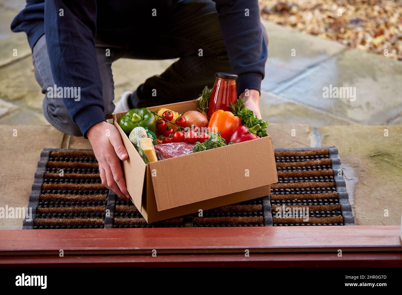 Mann Liefert Box Mit Frischen Zutaten Für Online-Mahlzeit Lebensmittel Rezept Kit Nach Hause Vor Der Haustür Stockfoto
