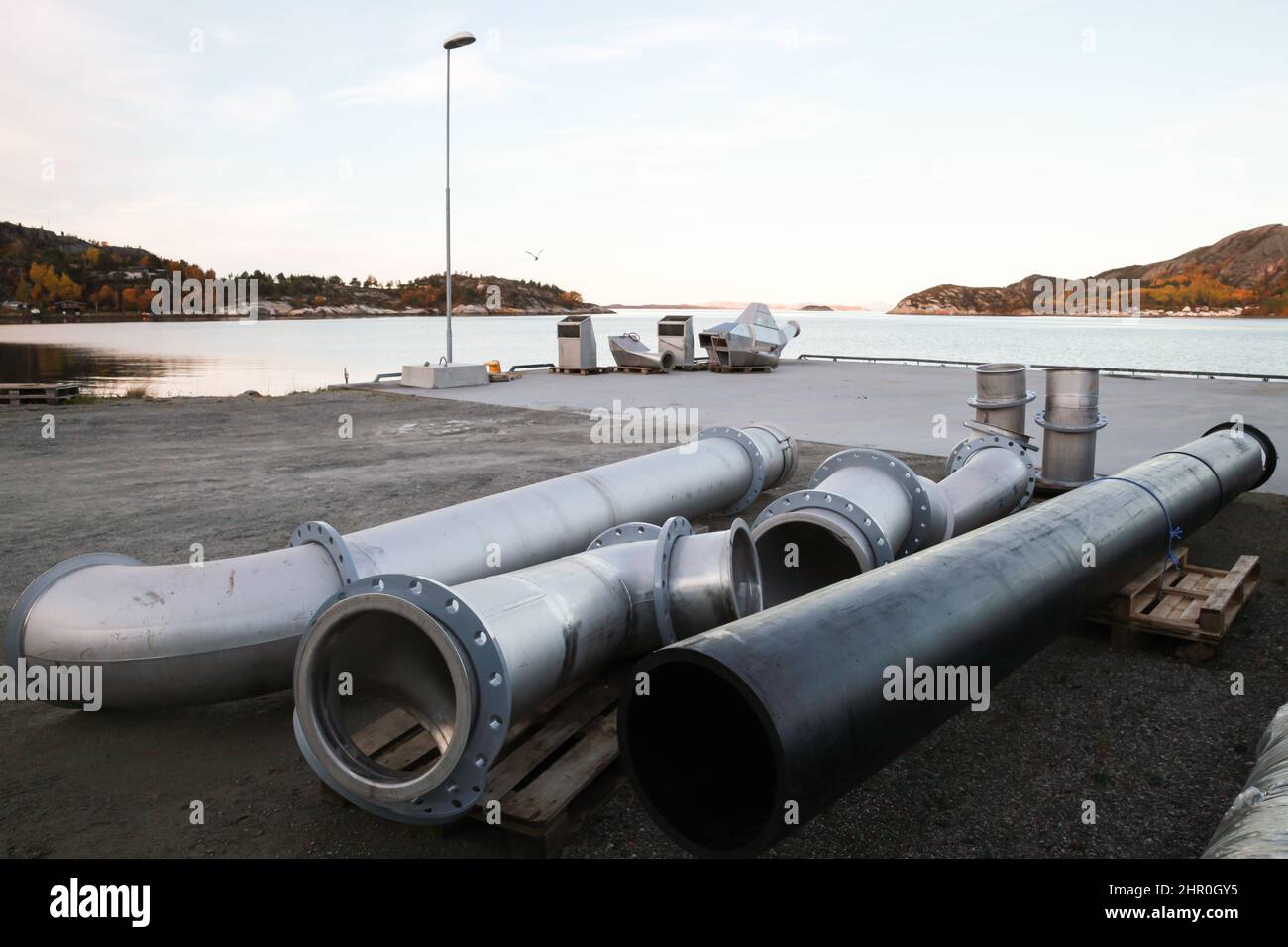 Metallrohre lagen auf dem Boden eines kleinen Frachthafens in Norwegen Stockfoto