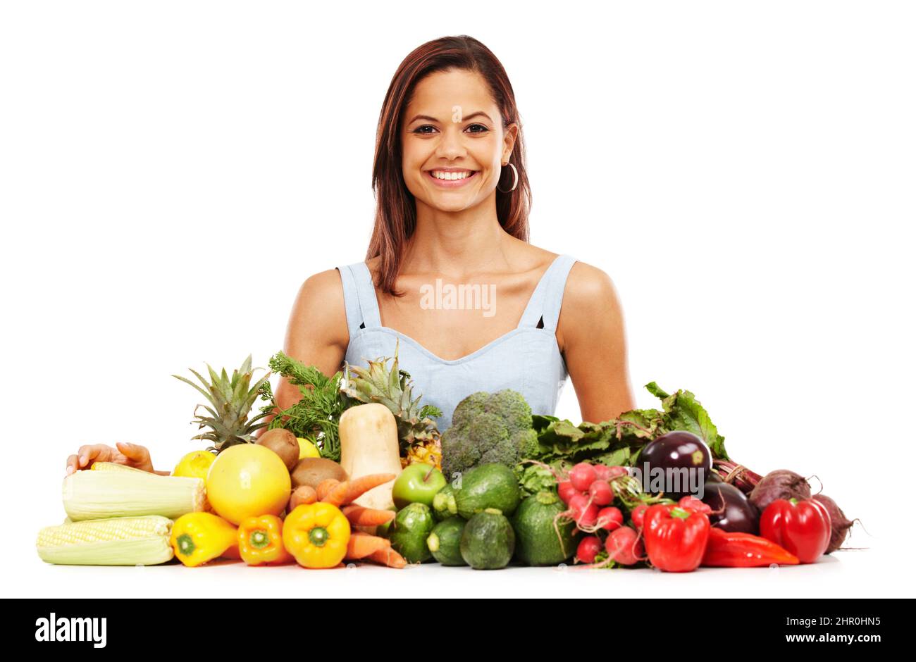 Sich über gesunde Entscheidungen sehr wohl fühlen. Lächelnde junge Frau neben einer Auswahl an gesundem und frischem Gemüse. Stockfoto
