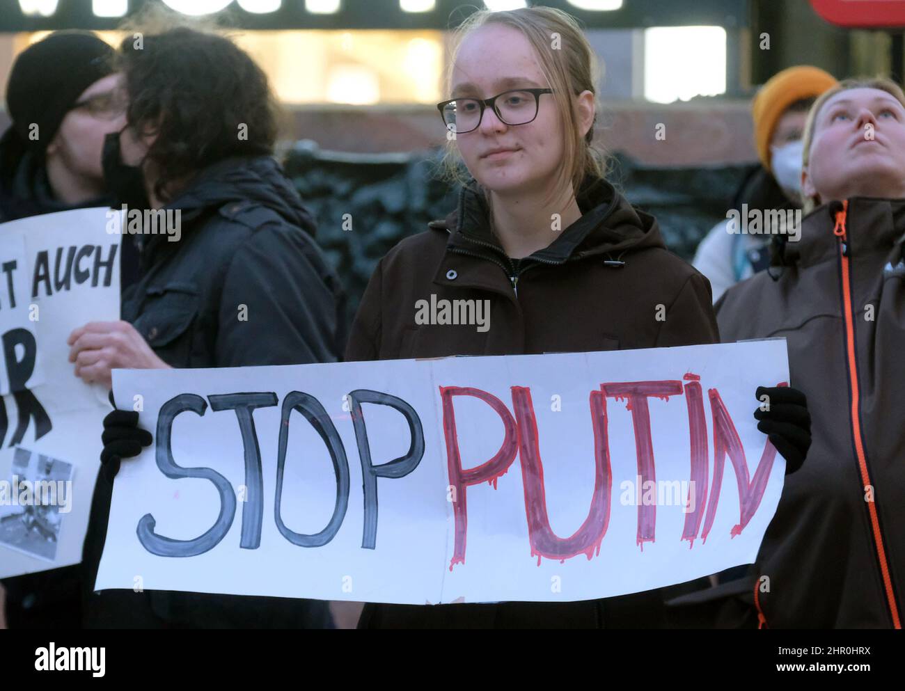 Leipzig, Deutschland. 24th. Februar 2022. Eine Frau hält bei einer Kundgebung auf dem Marktplatz ein Schild mit der Aufschrift „Stoppt Putin“. Mehrere hundert Menschen demonstrieren ihre Solidarität mit der Ukraine und gegen den Einmarsch russischer Truppen im Land. Quelle: Sebastian Willnow/dpa-Zentralbild/dpa/Alamy Live News Stockfoto