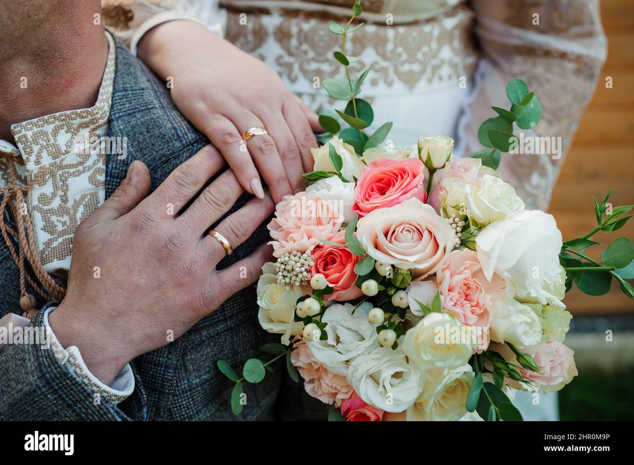 Goldene Eheringe, Hände der Braut und des Bräutigams auf einem Blumenstrauß Stockfoto