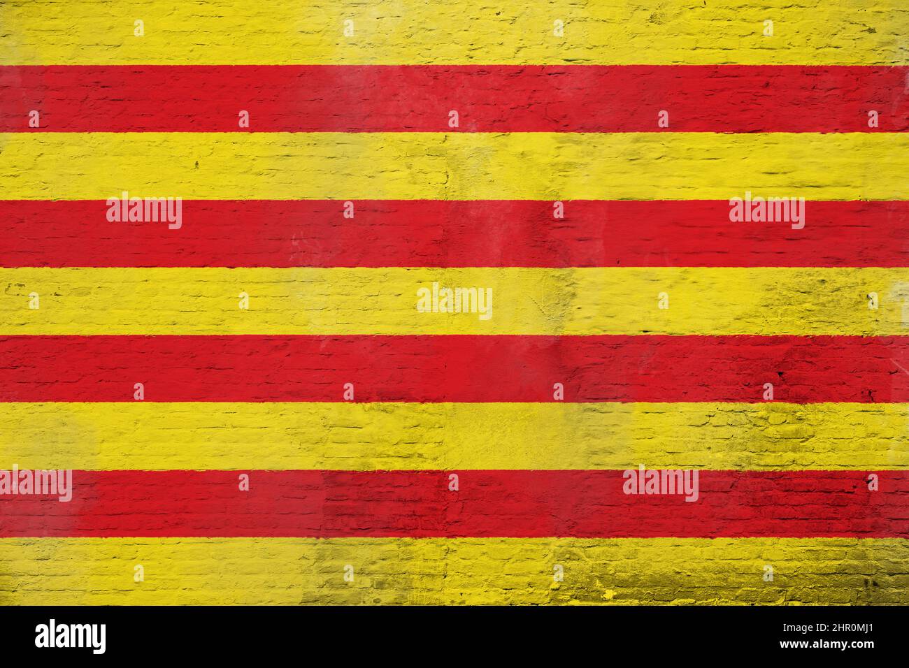 Vollformatfoto einer verwitterten Flagge Kataloniens auf einer verputzten Ziegelwand. Stockfoto