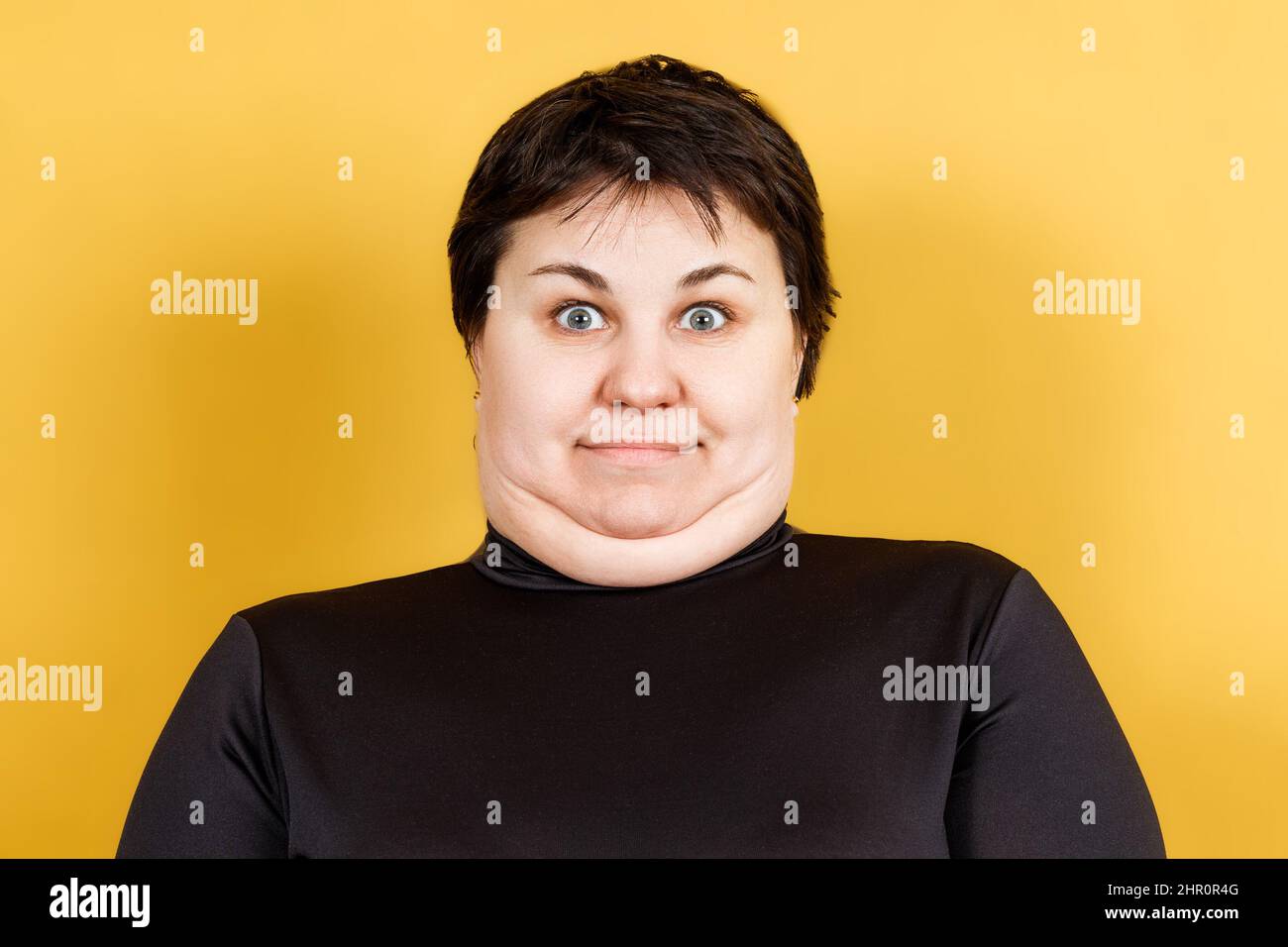 Fette Frau mit Doppelkinn und verrücktem Look auf gelbem Hintergrund Stockfoto