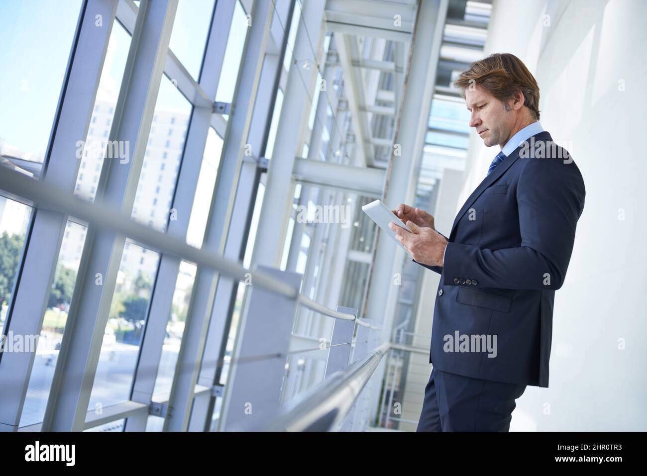 Business-Apps, die die Verwaltung erleichtern. Aufnahme eines reifen Geschäftsmannes, der mit einem digitalen Tablet in einem Büroflur steht. Stockfoto
