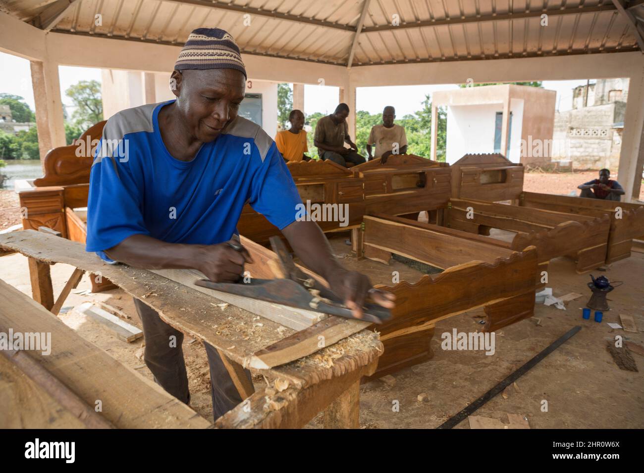 Erwachsener afrikanischer Holzarbeiter, der Holz in einer Schreinerei in Kolda, Senegal, Westafrika, plaziere. Stockfoto