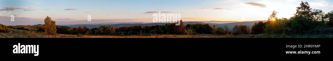 Wunderschönes Herbstpanorama von gelben und roten Bäumen vor dem Hintergrund großer Berge Stockfoto