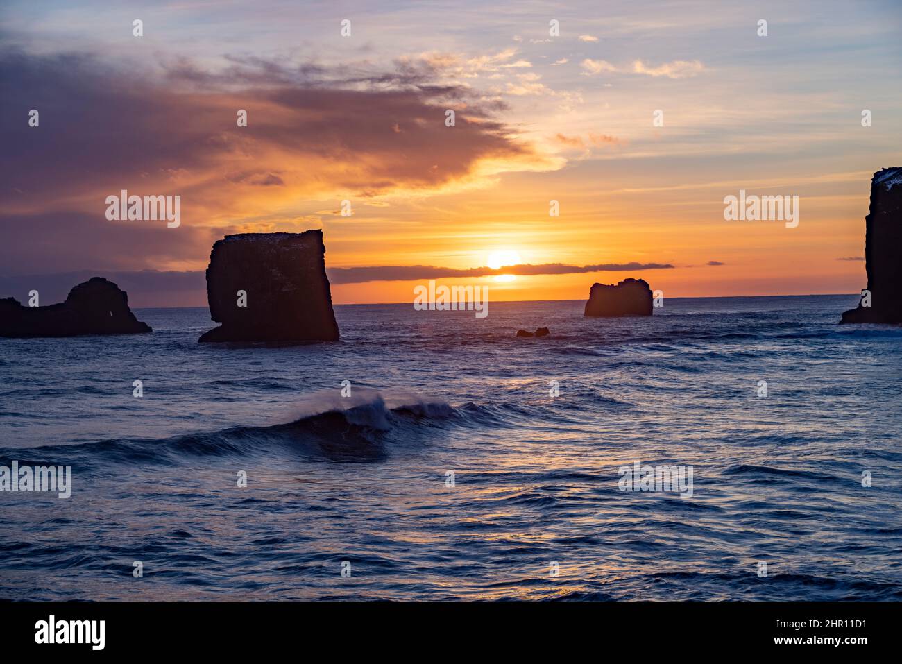 Blick auf Felsen und stürmisches Meer bei Sonnenuntergang von der Halbinsel Dyrholaey im Südosten Islands Stockfoto