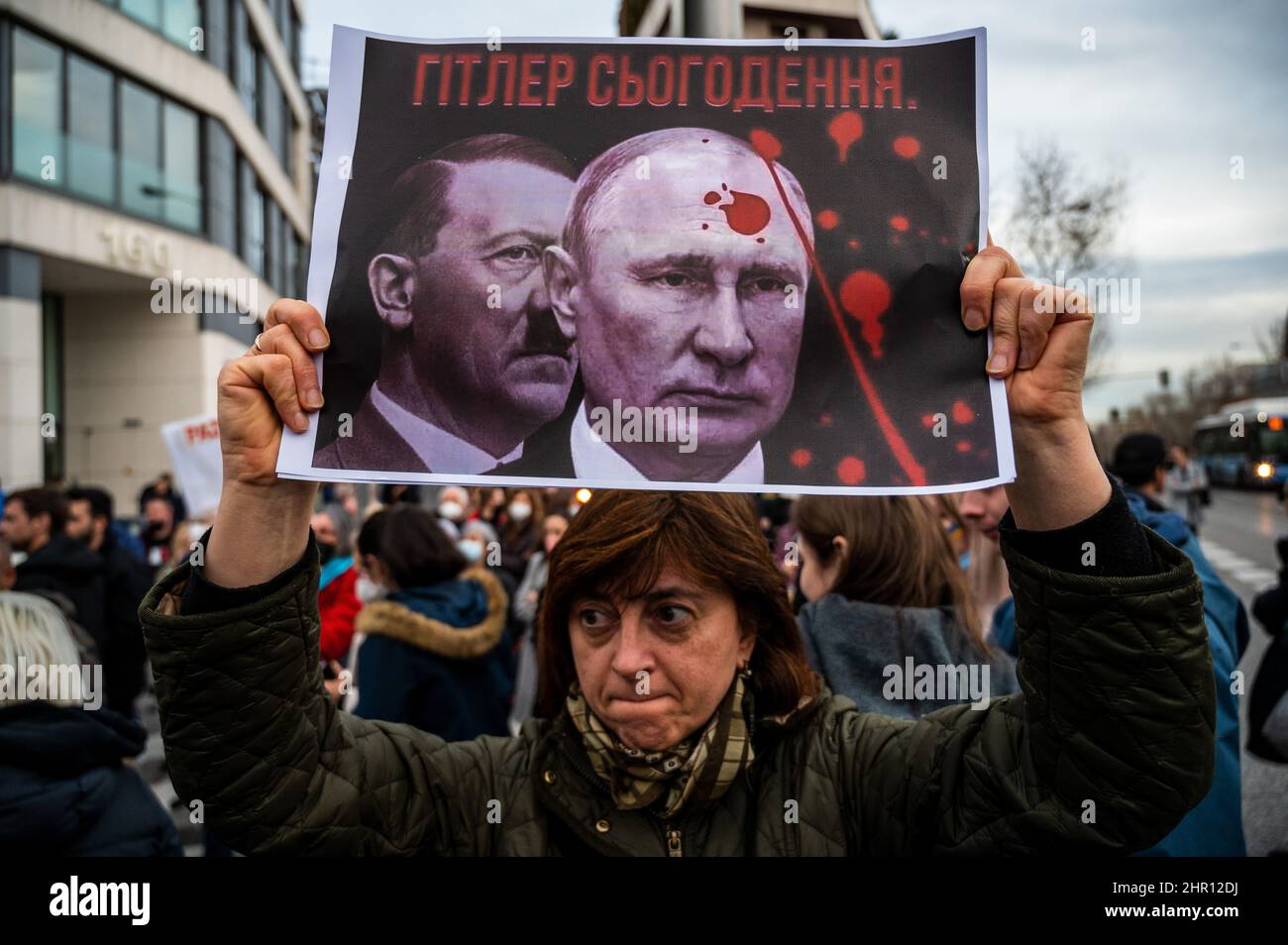 Madrid, Spanien. 24th. Februar 2022. Eine Frau ist mit einem Plakat zu sehen, auf dem die Bilder von Putin und Hitler während eines Protestes nach den ersten russischen Angriffen in der Ukraine gezeigt werden. In Madrid lebende Ukrainer versammelten sich vor der russischen Botschaft, um gegen die in mehreren Teilen des ukrainischen Landes registrierten russischen Angriffe zu protestieren, die das Ende des Krieges forderten und Parolen gegen den russischen Präsidenten Wladimir Putin riefen. Quelle: Marcos del Mazo/Alamy Live News Stockfoto