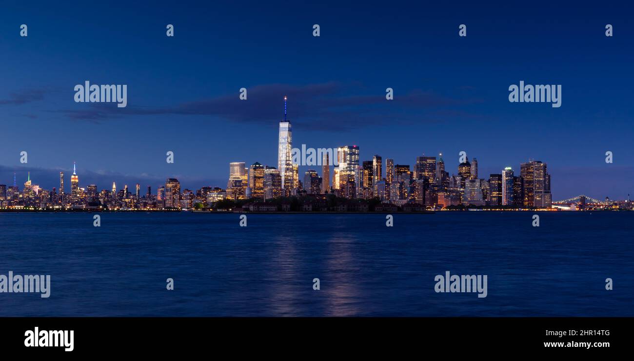 New York City Stadtbild in Lower Manhattan am Abend. Blick auf die Wolkenkratzer im Finanzdistrikt mit dem World Trade Center, Midtown West und Ellis Island Stockfoto