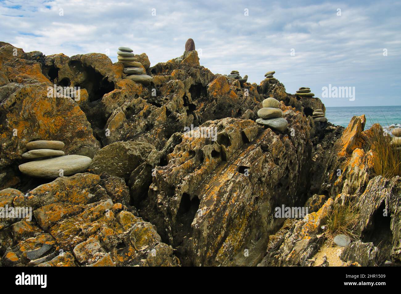 Kleine steinhaufen aus glatten Steinen auf einem verwitterten Felsen am Cape Conran, Victoria, Australien Stockfoto