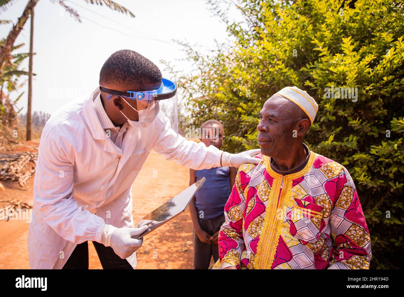Ein afrikanischer Arzt besucht einen älteren Patienten und unterhält sich während der medizinischen Untersuchung. Health Care in africa Konzept Stockfoto