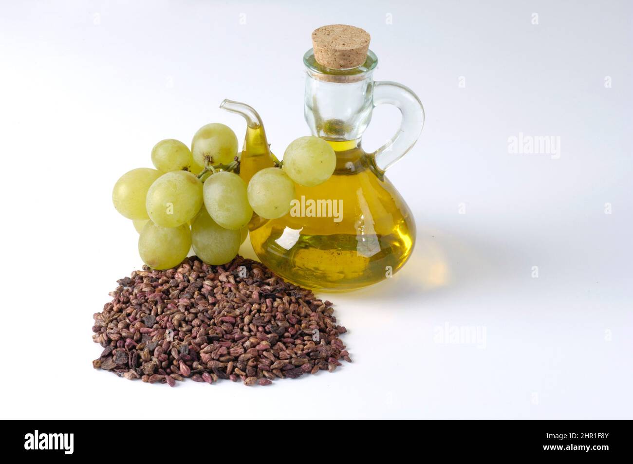 Weinrebe, Weinrebe (Vitis vinifera), Traubenkernöl mit grünen Trauben und getrockneten Traubenkernen Stockfoto