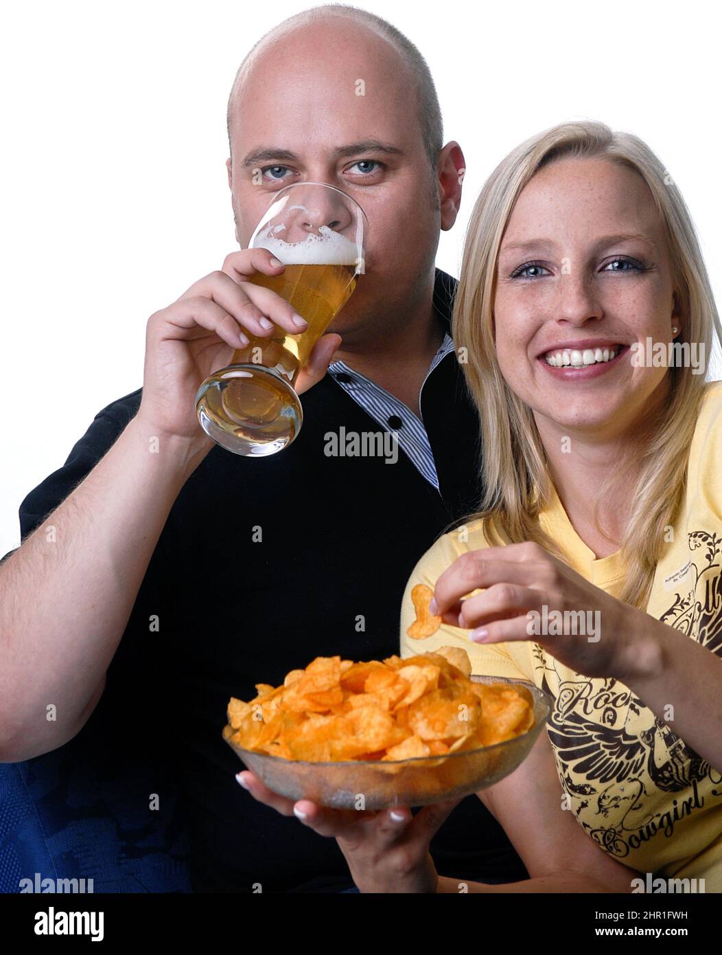 Das Paar genießt einen gemütlichen Abend beim Fernsehen mit einer Schüssel Chips und einem Glas Bier Stockfoto